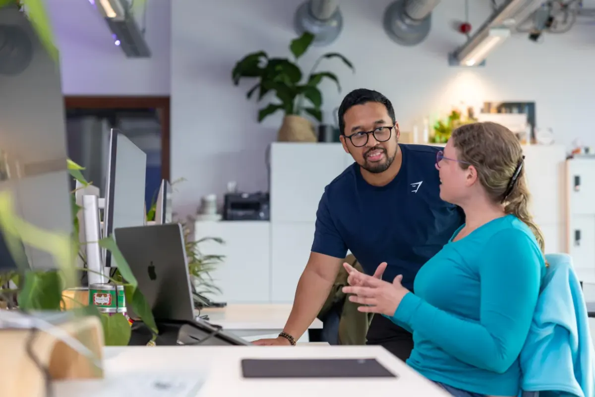 Twee collega's werken samen achter een laptop
